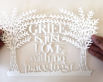 May include: White paper cut-out art with two trees and the text "GRIEF is just LOVE with no place to go."