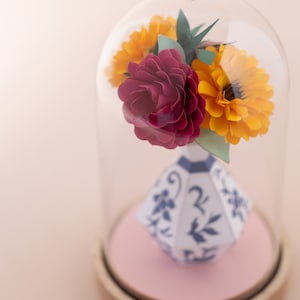 a paper vase with paper flowers inside in a plastic dome, zoom view. this is a kit by my papercut forest