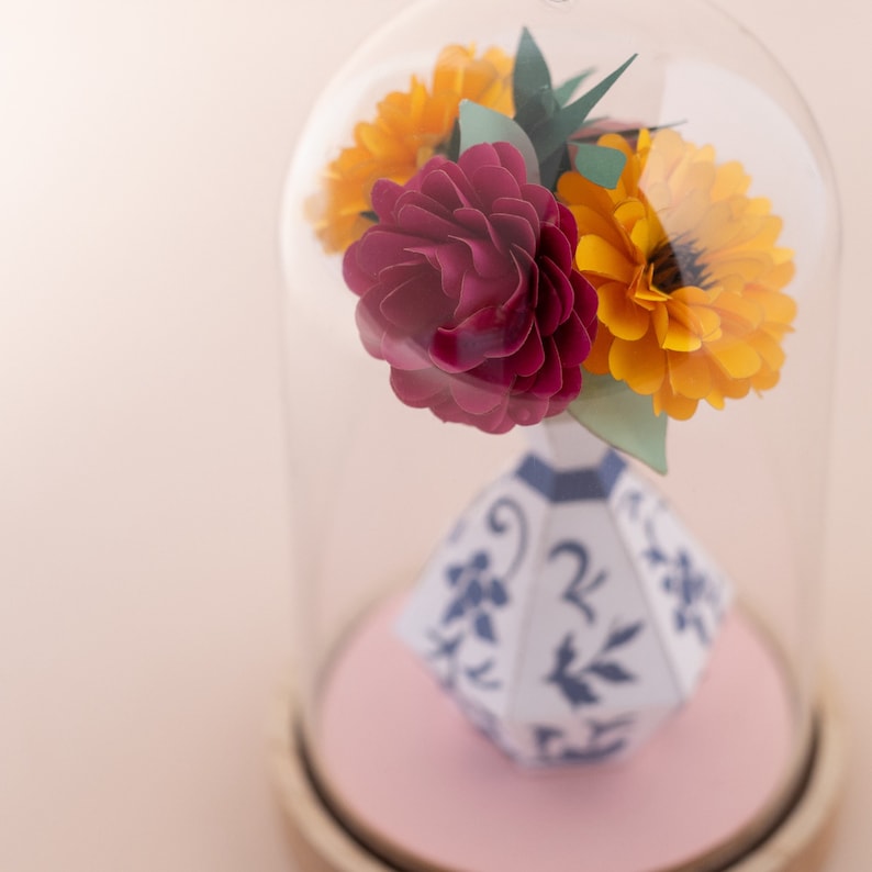 a paper vase with paper flowers inside in a plastic dome, zoom view. this is a kit by my papercut forest