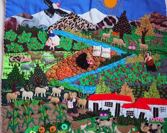 May include: A colorful fabric wall hanging featuring a landscape scene with embroidered mountains, a sun, a river, and various animals including sheep, llamas, and cows. The scene includes small figures, houses with red roofs, and two sacks labeled PAPA.