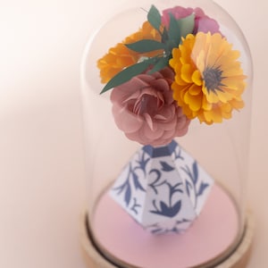 a paper vase with paper flowers inside in a plastic dome, zoom view. this is a kit by my papercut forest