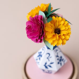 a paper vase with paper flowers inside in a plastic dome, zoom view. this is a kit by my papercut forest