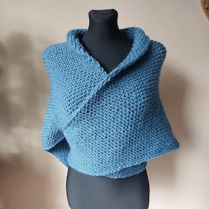 May include: A blue knitted shawl with a cowl neck. The shawl is draped over a black mannequin.