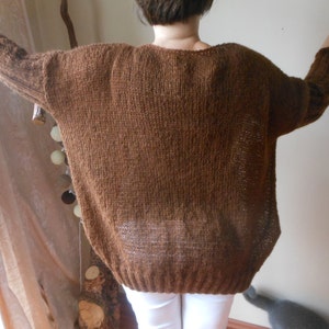 May include: A brown knitted sweater with a loose fit and long sleeves.