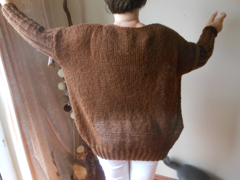 May include: A brown knitted sweater with a loose fit and long sleeves.