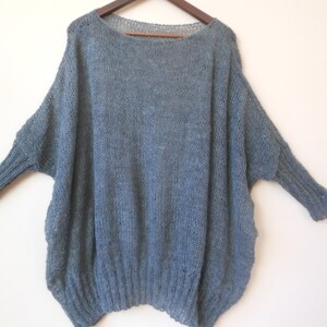 May include: A loose-fitting, gray knitted sweater with long sleeves.