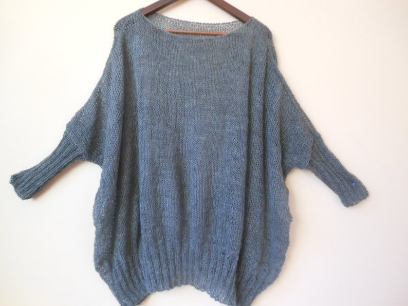 May include: A loose-fitting, gray knitted sweater with long sleeves.