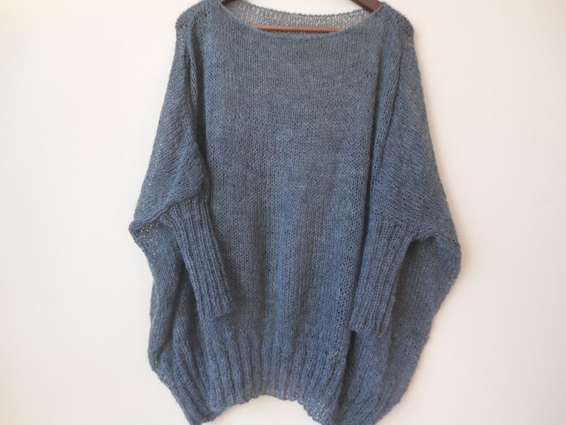 May include: A loose-fitting, light blue knitted sweater with long sleeves and a wide neckline.