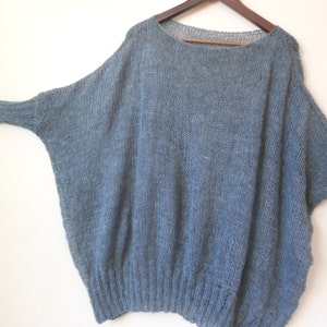 May include: A loose-fitting, blue knitted sweater with long sleeves.