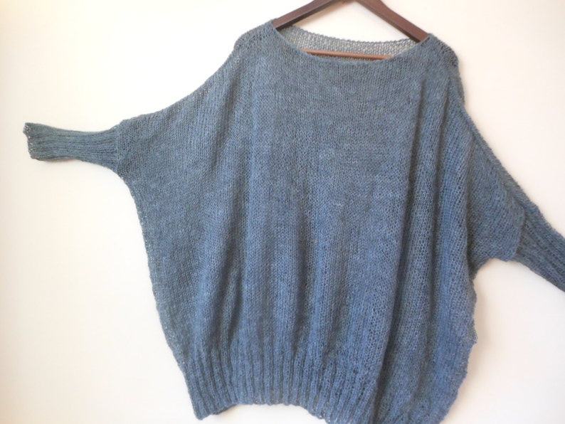May include: A loose-fitting, blue knitted sweater with long sleeves.