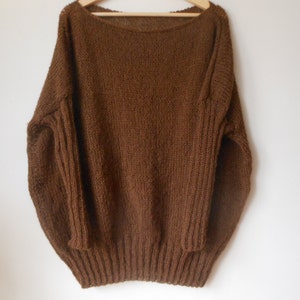 May include: A brown knitted sweater with a wide neckline and long sleeves.