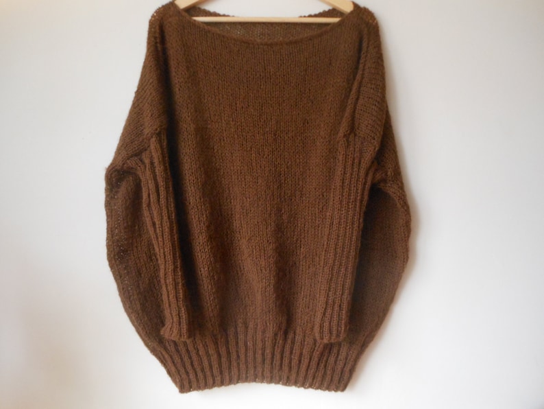 May include: A brown knitted sweater with a wide neckline and long sleeves.