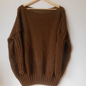 May include: A brown knitted sweater with a wide neckline and long sleeves.