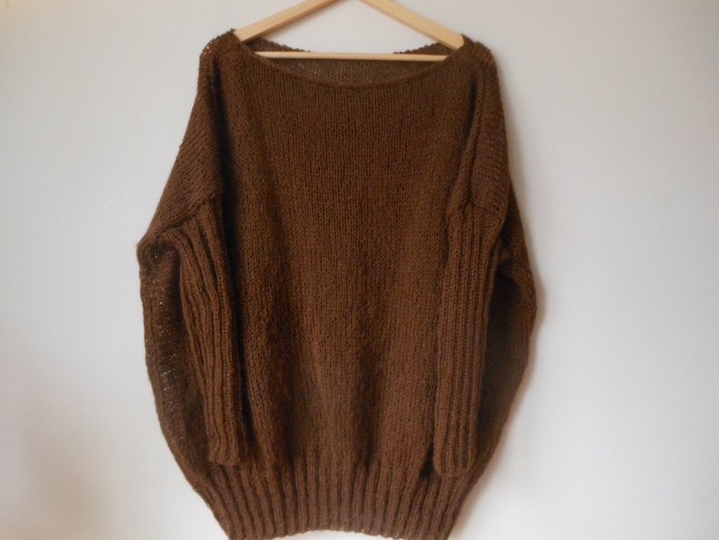 May include: A brown knitted sweater with a wide neckline and long sleeves.