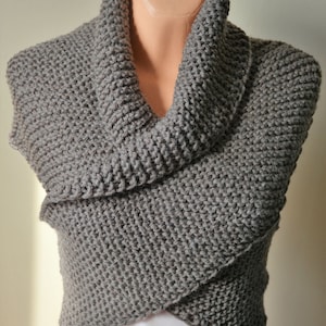 May include: A gray cowl neck knitted scarf. The scarf is made of a soft, chunky yarn and has a relaxed, drapey fit.