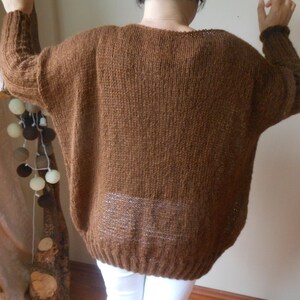 May include: A brown knitted sweater with a loose fit and long sleeves.