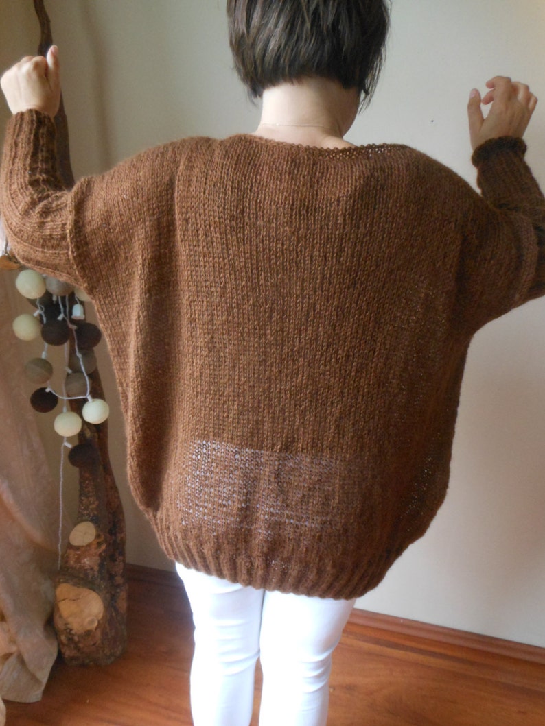 May include: A brown knitted sweater with a loose fit and long sleeves.