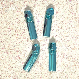 May include: Four light blue zipper pulls with a metallic finish. The zipper pulls are rectangular in shape and have a small loop at the top.