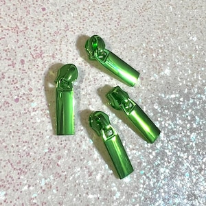 May include: Four green metal zipper pulls. The pulls are rectangular in shape with a shiny metallic finish.