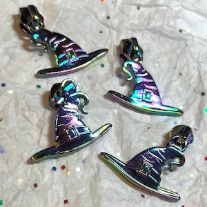 May include: Four iridescent witch hat zipper pulls. The zipper pulls are made of metal and have a rainbow finish. They are perfect for adding a touch of whimsy to any project.