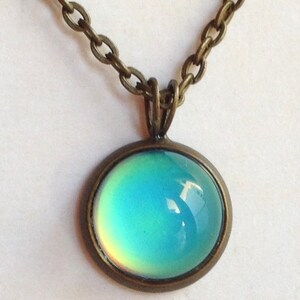 May include: A bronze chain necklace with a round pendant featuring a blue iridescent glass cabochon.