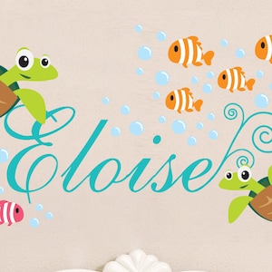 May include: A teal blue cursive name "Eloise" with two green sea turtles and orange and white striped fish swimming around bubbles.