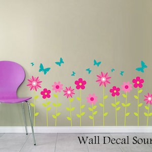 May include: Wall decal featuring a row of pink and green flowers with teal butterflies. The decal is applied to a light beige wall with a purple chair in the foreground.
