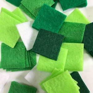 May include: A collection of green, white, and light green felt squares. The squares are various sizes and are arranged in a random pattern.