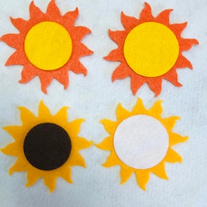 May include: Four felt sun shapes, two orange with yellow centers, one yellow with a black center, and one yellow with a white center.