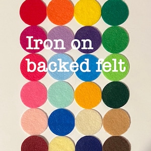 May include: Assortment of 18 iron-on backed felt circles in various colors, including red, orange, yellow, green, purple, blue, pink, light blue, brown, beige, cream, and navy. The text "Iron on backed felt" is written in white letters on a white background.