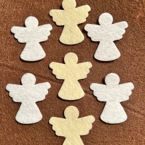 May include: Eight felt angel shapes, four are white and four are cream colored. The angels are arranged in a symmetrical pattern on a brown background.
