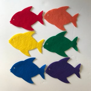 May include: Six felt fish in different colors: red, orange, yellow, green, blue, and purple. The fish are all the same shape and size.