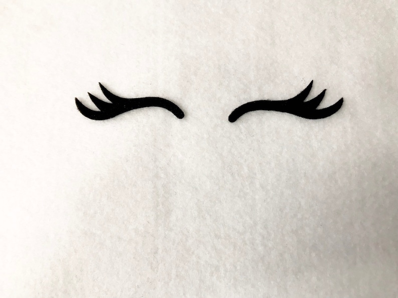 May include: Two black eyelashes, each with three points, are arranged in a curved shape, resembling a pair of eyes. The eyelashes are on a white background.