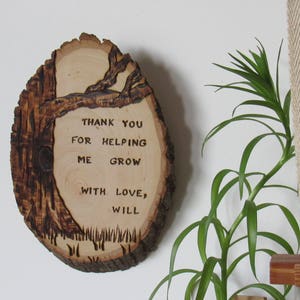 May include: A wooden tree slice with the text "Thank you for helping me grow with love, Will" burned into the surface.