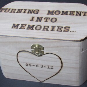 May include: A wooden box with a hinged lid and a brass latch. The box is engraved with the words "Turning Moments Into Memories..." and the date "08-03-12".