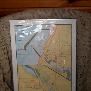 Könnte beinhalten: Eine Vintage-Karte von Leland, Michigan, die die Lage des Lake Michigan, des Lake Leelanau und des Carp River zeigt. Die Karte ist auf cremefarbenem Papier gedruckt und hat einen hellbraunen Rand.