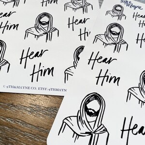 Peut inclure: Un ensemble d'autocollants noir et blanc repr&eacute;sentant un dessin au trait d'une personne avec une barbe et le texte "Hear Him".