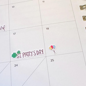 May include: A white calendar page with stickers. One sticker says "spring forward" in cursive. Another says "St. Patty's Day" with a green shamrock. A third sticker shows a bunch of balloons.