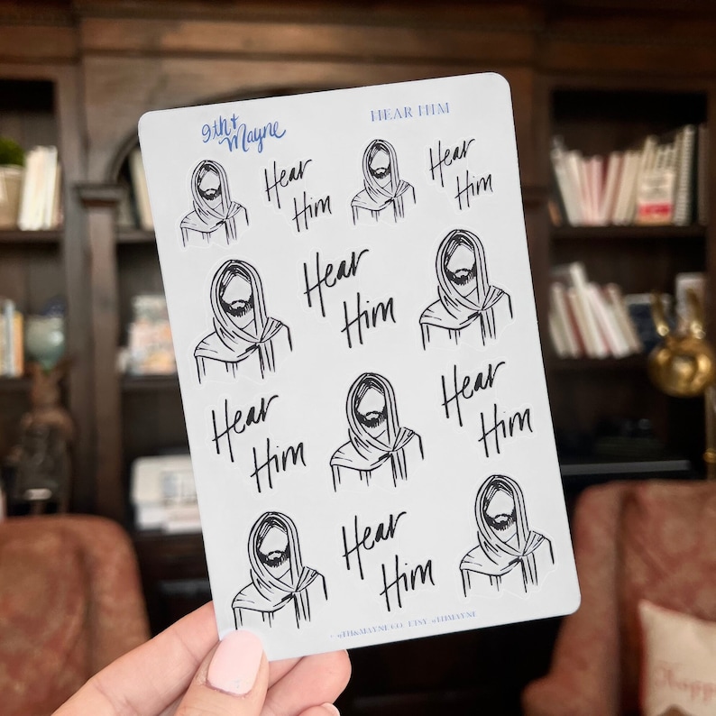 Peut inclure: Une feuille d'autocollants avec une illustration en noir et blanc d'un homme barbu et le texte "Hear Him" r&eacute;p&eacute;t&eacute; plusieurs fois.