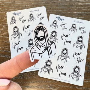 Peut inclure: Une feuille d'autocollants blancs avec des illustrations noires d'une personne avec une barbe et le texte "Hear Him".