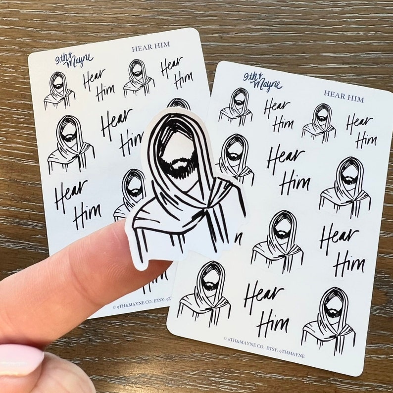 Peut inclure: Une feuille d'autocollants blancs avec des illustrations noires d'une personne avec une barbe et le texte "Hear Him".