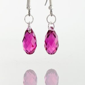 May include: A pair of silver dangle earrings with pink teardrop-shaped crystal beads.