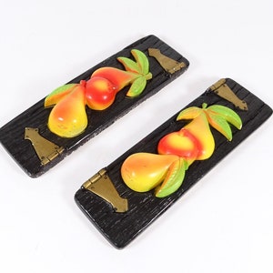 May include: Two wooden plaques with a 3D design of pears and peaches. The plaques are painted black with gold accents. The fruit is painted in shades of yellow, orange, red, and green.