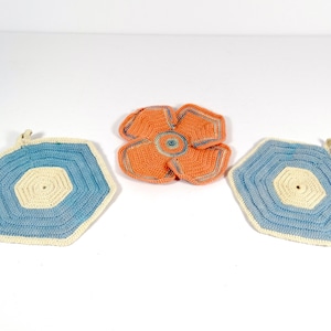 May include: Three crocheted pot holders. One is a flower shape in orange and white. The other two are octagons in blue and white.
