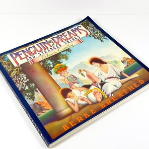 May include: A book titled "Penguin Dreams and Stranger Things in Bloom County" by Berke Breathed. The cover features a colorful illustration of three figures in a garden setting.