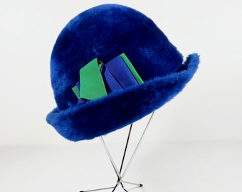 May include: A blue fuzzy hat with a green and blue ribbon on a silver stand.