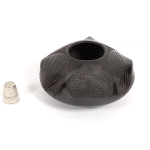 May include: A black ceramic bowl with a carved design. The bowl is round and has a wide opening. It is about 4 inches in diameter.