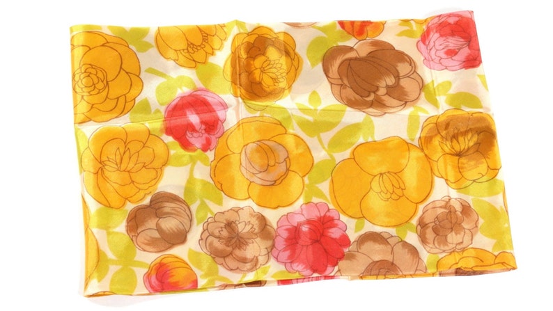 Pode incluir: Um len&ccedil;o de seda com estampa floral amarela, marrom e rosa. O len&ccedil;o tem um fundo branco com um padr&atilde;o repetido de flores.