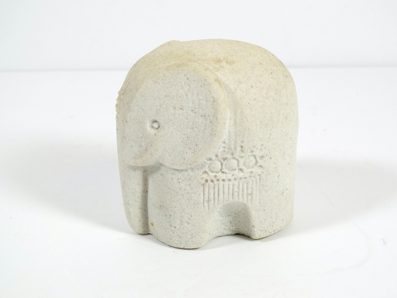 Peut inclure: Une petite figurine d'&eacute;l&eacute;phant en pierre blanche. L'&eacute;l&eacute;phant a une surface textur&eacute;e et un motif d&eacute;taill&eacute; sur son dos.