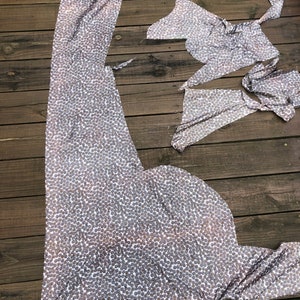 Puede incluir: Piezas de tela con un estampado de lunares plateados y blancos est&aacute;n dispuestas sobre una terraza de madera. La tela parece estar cortada en varias formas, posiblemente para coser una prenda. La imagen est&aacute; tomada desde arriba.